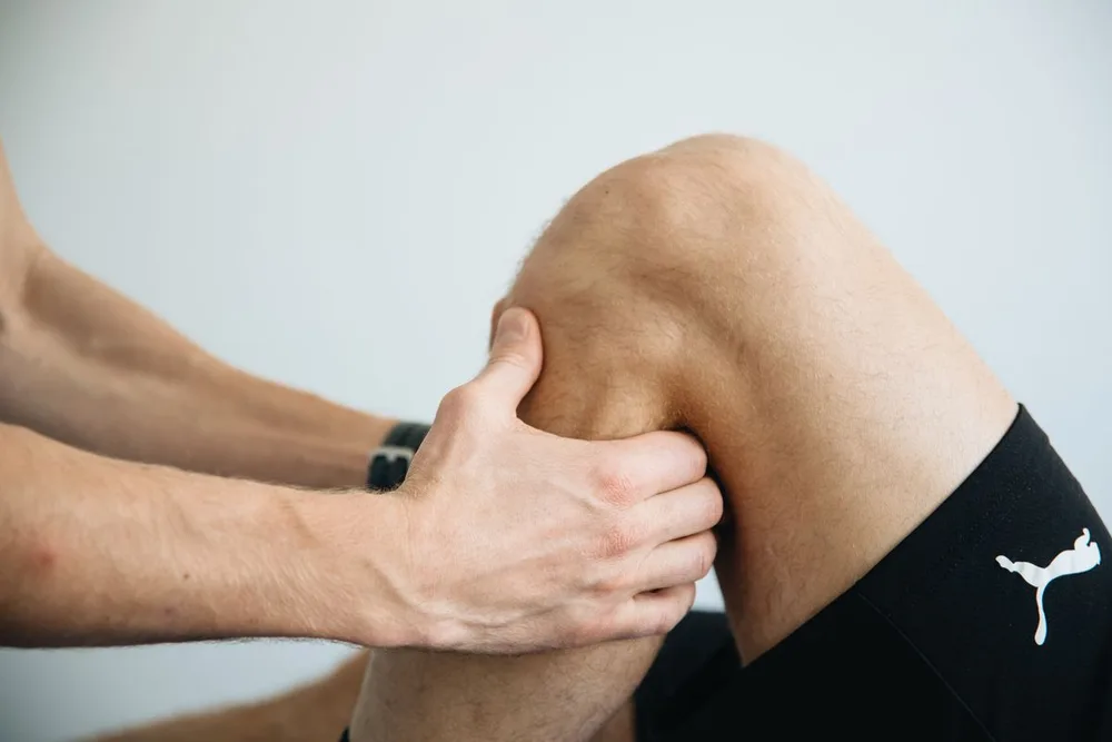 Hands applying and massaging a topical cream into a knee joint